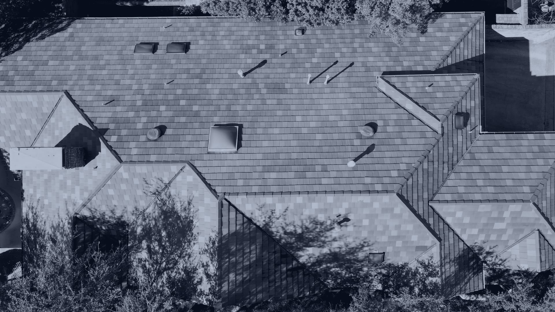 Overhead drone photograph of a residential roof filling the frame, every slope, valley and vent stack visible in one plane — the kind of roof documented on property damage claims in Plano.