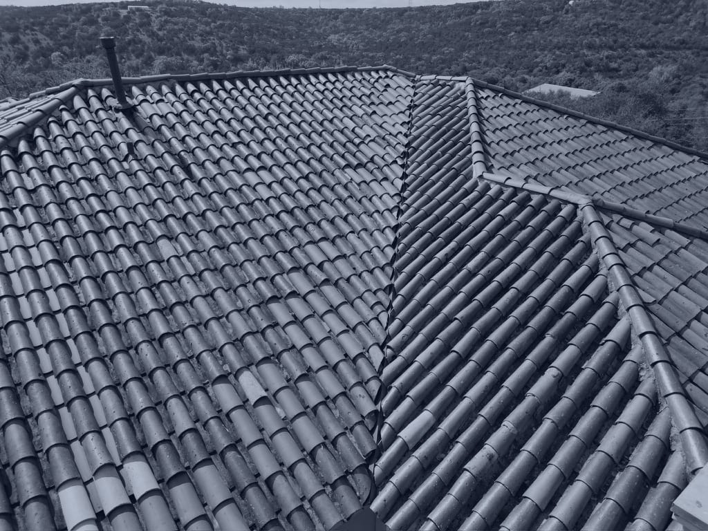 Aerial photograph of a clay tile roof's slopes and valleys running out to open country, taken from a drone — the kind of roof documented on property damage claims in McKinney.