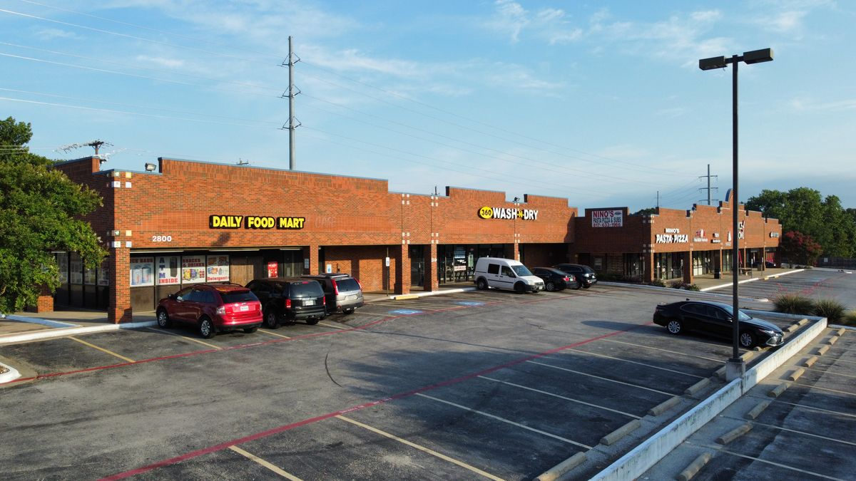 A brick strip retail center with storefronts and a parking lot